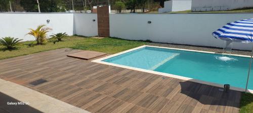 a swimming pool in a yard next to a white wall at Casa Condomínio Ninho Verde II in Pardinho