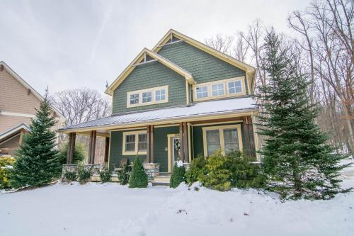 a green house with trees in the snow at Bear Foot by Railey Vacations in Oakland