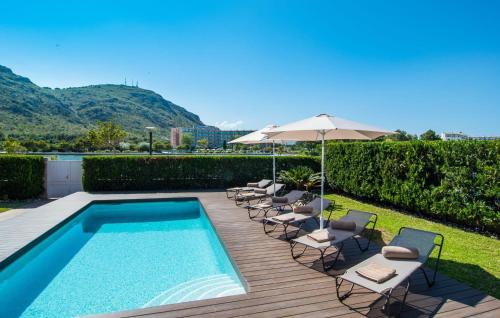 a swimming pool with lounge chairs and an umbrella and a pool at Montelago in Alcudia