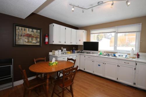 cocina con mesa y cocina con armarios blancos en Jenny's Guest House, en Yellowknife