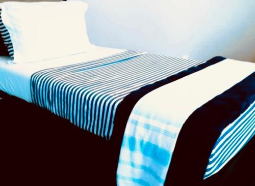 a bed with a blue and white striped sheets and a pillow at House FLL airport in Fort Lauderdale