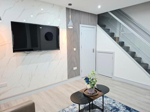 a living room with a table and a tv on a wall at New & Lovely Spacious 2-Bedroom Villa in Coventry