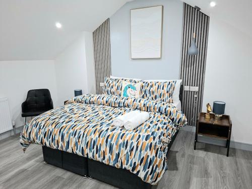 a bedroom with a bed with a striped comforter and a chair at New & Lovely Spacious 2-Bedroom Villa in Coventry