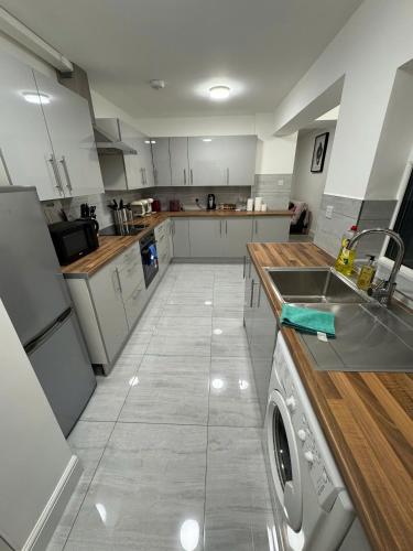 a large kitchen with white cabinets and a dishwasher at 96 Nelgarde Guesthouse in London