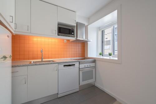 a kitchen with white cabinets and a sink and a window at Authentic Porto Home by HostWise in Porto