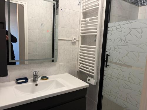 a white bathroom with a sink and a mirror at Appartement face océan in Lacanau