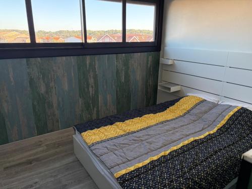 a bed in a room with two windows in a room at Appartement face océan in Lacanau