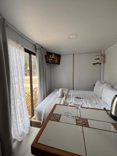 a bedroom with a bed and two wine glasses on a table at Nomade Balmaceda in Balmaceda