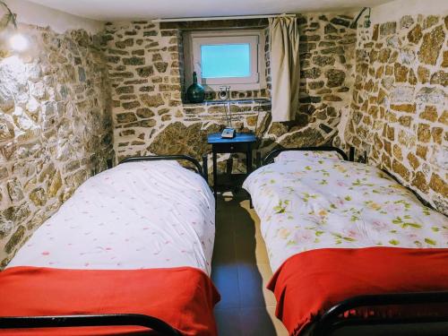 two beds in a room with stone walls at Au coeur de l'Ardenne - Peaceful loft in Baelen