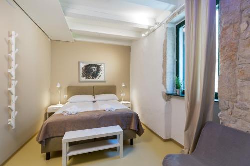 a bedroom with a bed and a chair and a window at Tre Porte Rooms & Bar in Rovinj