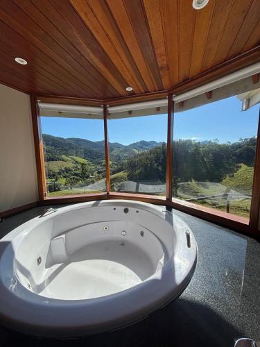 a large white tub in a room with windows at Chalé Pedra Madeira-Recanto Venâncio in São Bento do Sapucaí