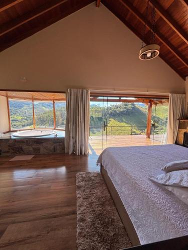 a bedroom with a bed and a large window at Chalé Pedra Madeira-Recanto Venâncio in São Bento do Sapucaí
