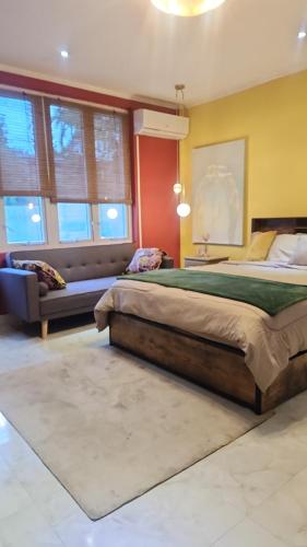 a bedroom with two beds and a couch and windows at Hilltop Villa Chez Coco in Rodney Bay Village