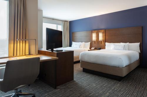 a hotel room with two beds and a desk at Residence Inn by Marriott Orlando at Millenia in Orlando