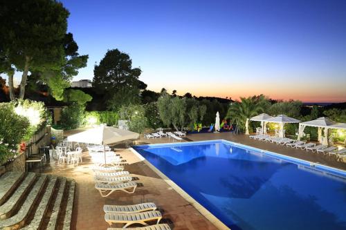 a swimming pool with chairs and umbrellas next to a resort at Hotel Club Bellavista in Vieste