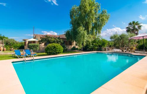 a swimming pool with two blue chairs and a house at Can Bleio in Pollença