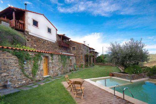 a house with a swimming pool next to a building at Bairro do Casal - Turismo d'Aldeia in Vila Nova de Foz Coa