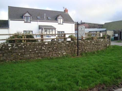 a stone fence in front of a house at The Farmhouse Lochmeyler in Llandeloy