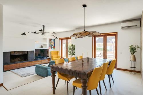 a dining room with a wooden table and yellow chairs at Beach Villa with Jacuzzi & Garage by HostWise in Vila Chã