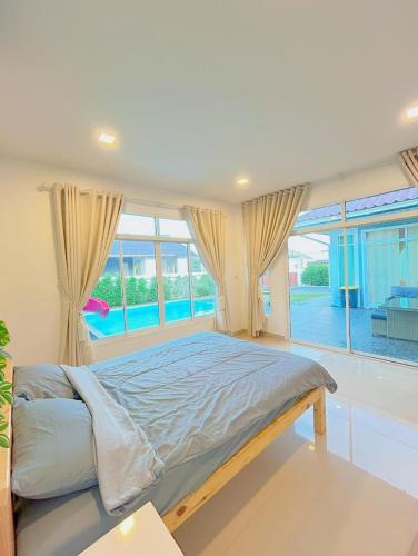 a bedroom with a large bed and a large window at Victoria Poolvilla Pattaya by Chon in Nong Prue