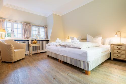 a bedroom with a large white bed and a chair at Ferienhaus Cäcilienhof West in Kampen
