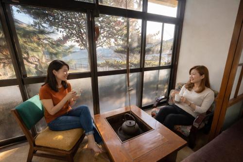 two women sitting in a room looking out the window at Nagasaki Horigotatsu Kominka Stay 掘りごたつの古民家1棟貸切 in Nagasaki