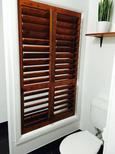 a bathroom with a toilet and a wooden window at Cottage on Cork Steadman Cottage in Winton