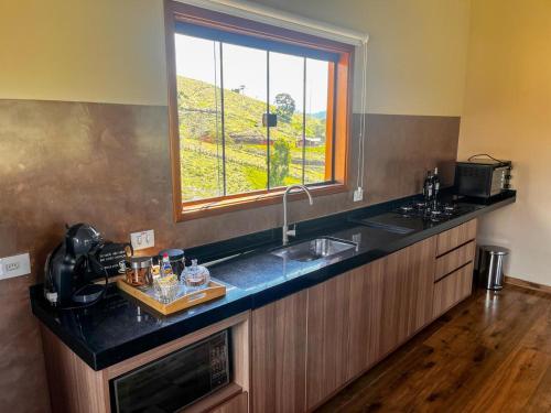 a kitchen with a sink and a window at Chalé Pedra Ferro-Recanto Venâncio in São Bento do Sapucaí