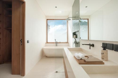 a white bathroom with a tub and a sink at Manu Villas in Sanur