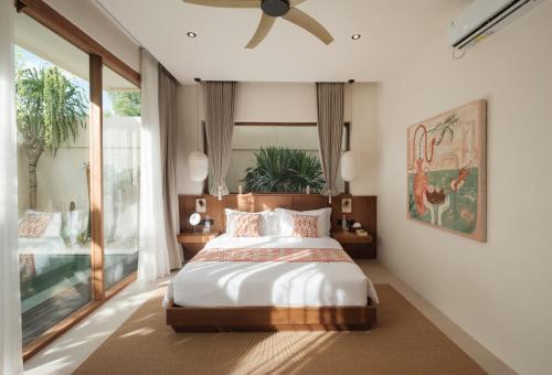 a bedroom with a bed and a ceiling fan at Manu Villas in Sanur