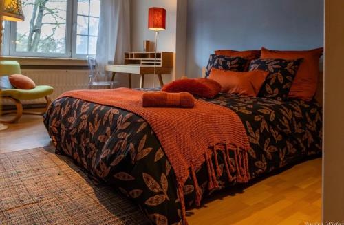a bedroom with a bed with an orange blanket at Villa des Bois Sauvages in Liège