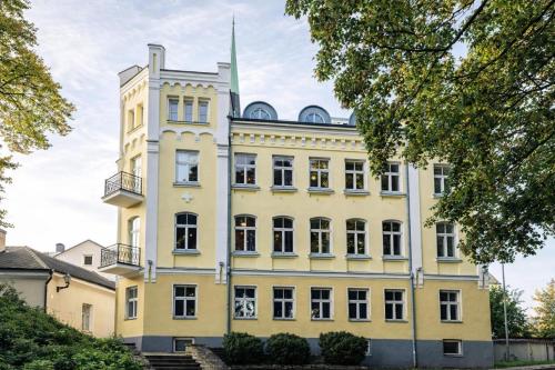 a large yellow building with a tower at Rija Old Town Hotel in Tallinn