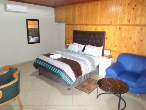 a bedroom with a bed and a blue chair at Daeka Guesthouse in Kempton Park
