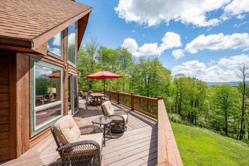 a deck with chairs and tables and an umbrella at The Cozy Perch by Railey Vacations in Oakland
