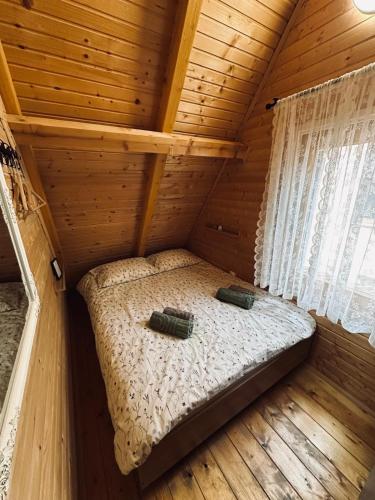 a small bed in a wooden cabin with windows at Planinski šapat in Blidinje