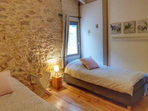 a bedroom with two beds and a stone wall at La Lumière Dorée in Lauzerte