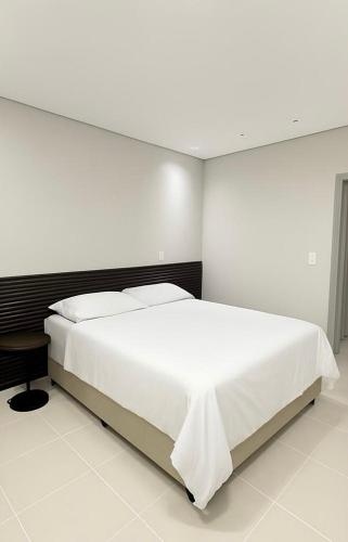 a bedroom with a large white bed and a table at Luxuoso Apartamento 2 quartos no Centro in Imperatriz