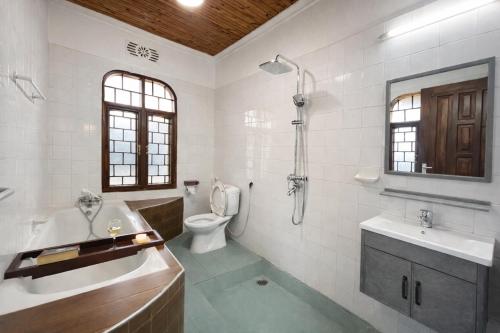 a bathroom with a tub and a toilet and a sink at Toiwo Residence 4BR Home in Ilboru, Arusha in Arusha