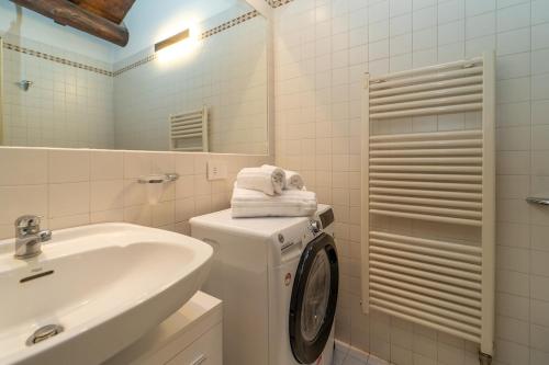 a white bathroom with a washing machine and a sink at Bright apartment with private garage in Cernobbio