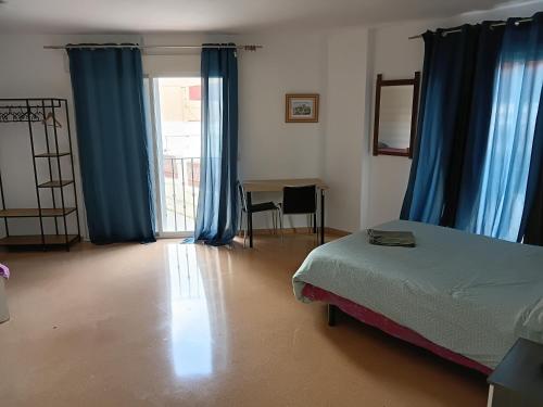 a bedroom with blue curtains and a bed and a desk at EMMI Guesthouse in Alicante