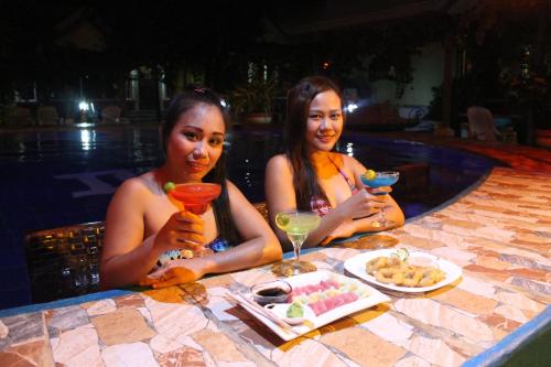 two women sitting at a table with drinks in a pool at Deep Forest Garden Hotel in Puerto Princesa City