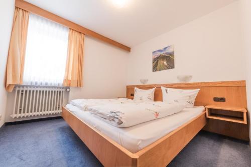 a bedroom with a large bed with white sheets at T13 Ferienwohnungen Schenk in Oberstdorf