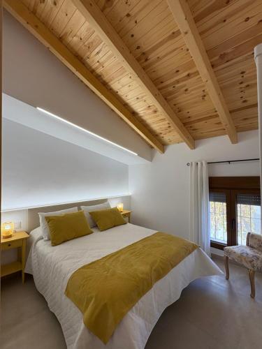 a bedroom with a large bed and a wooden ceiling at La Ermita Casa Rural in Benablón