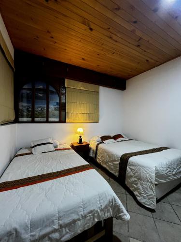a bedroom with two beds and a wooden ceiling at Rajutuna Inn in Huaraz