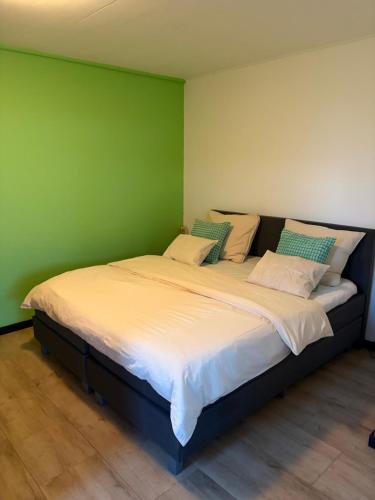 ein großes Bett in einem Zimmer mit einer grünen Wand in der Unterkunft B&B de Danser in Klaaswaal