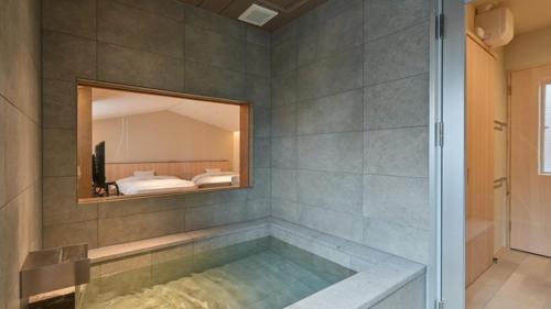 a bathroom with a tub with a mirror and a bed at Ureshino Onsen Yusyuku Sarayama in Ureshino
