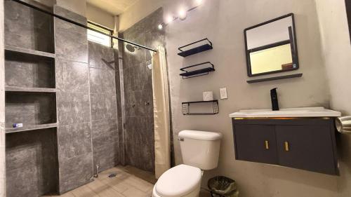 a bathroom with a shower and a toilet and a sink at Estudios Hotel Colonial in Escárcega