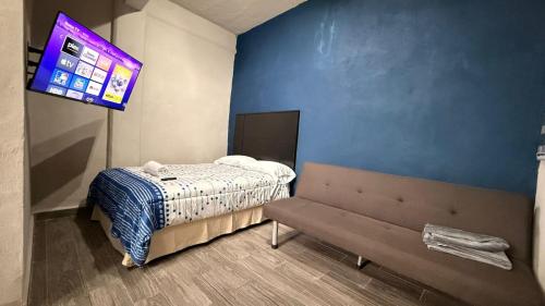 a bedroom with a bed and a tv on the wall at Estudios Hotel Colonial in Escárcega