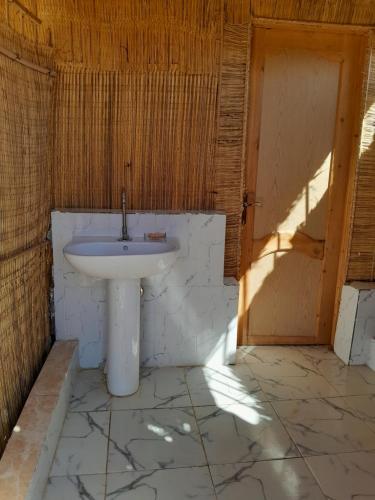 a bathroom with a white sink and a door at Energy camp in Bawati