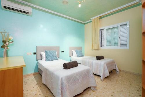 two beds in a room with blue walls at Villa Sunset - San Antonio Bay in Cala de Bou